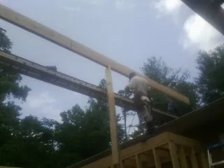 Carpenter setting a ridge beam over a new addition frame — Ice Dam Removal by Roofing Brothers in Cedar Vale