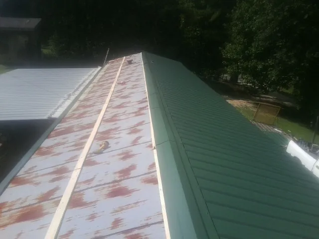 Old rusted panels beside newly installed green metal roofing — Wind Damage Roof Repair by Roofing Brothers in Cedar Vale