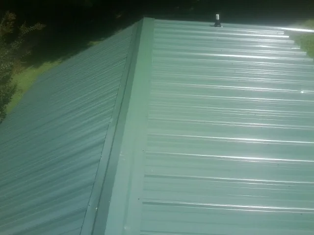 New green metal panels meeting at the ridge of a roof — Flat Roof Repair work by our crew in Cedar Vale