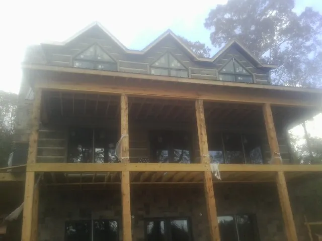 Dormers and porch framing on a large log home under construction — Roof Coating work by our crew in Cedar Vale