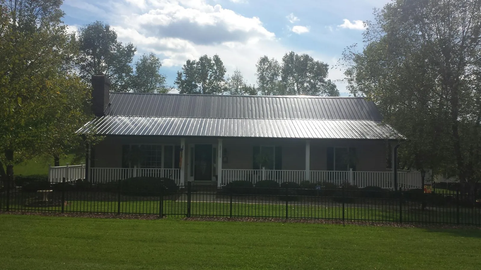 Gray metal roof on a brick ranch with a full width front porch — Gutter Guard Installation work by our crew in Cedar Vale