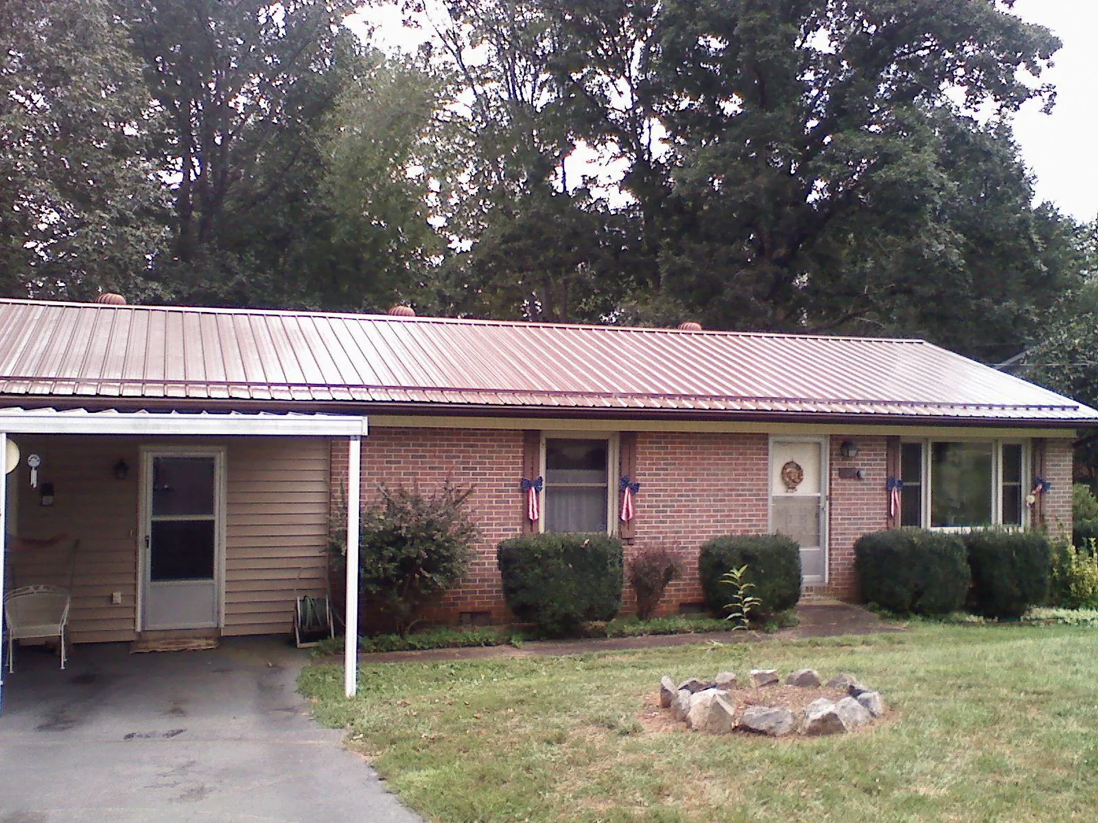 Bronze metal roof and carport on a brick ranch home — Roof Repair work by our crew in Cedar Vale
