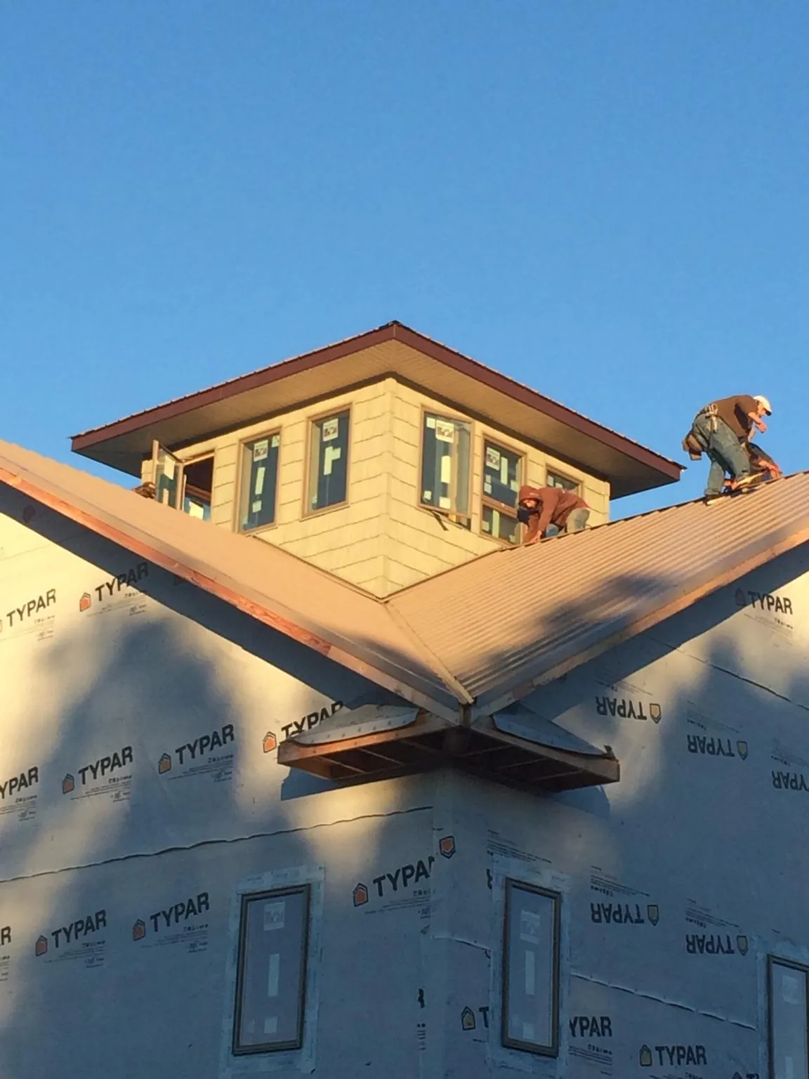 Roofers working around a rooftop cupola on a new metal roof at sunset — Roof Waterproofing in Cedar Vale by Roofing Brothers